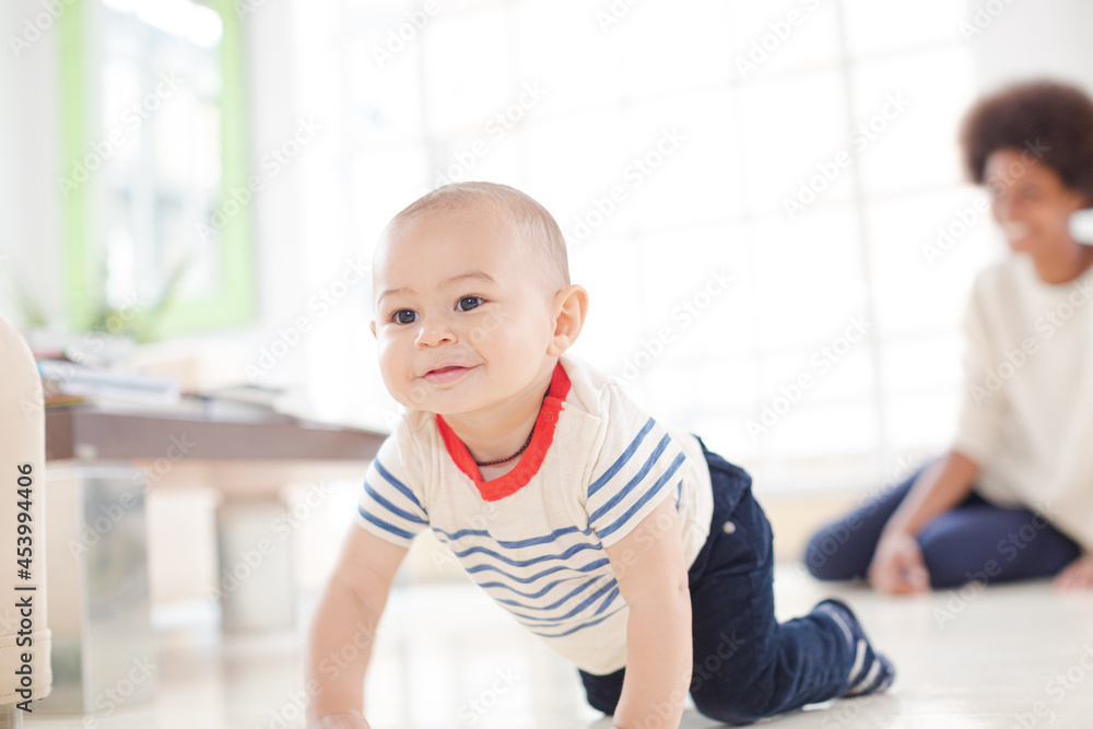 Mother watching baby boy crawl on floor Mother watching baby boy crawl on floor