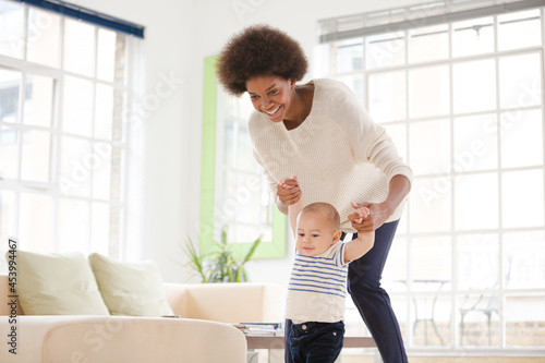 Free Download Mother helping baby boy walk in living room - GFXLoad