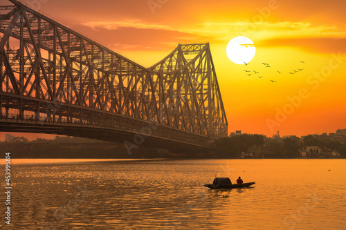 Howrah bridge with fishing boat on river Ganges at sunrise at Kolkata India photo