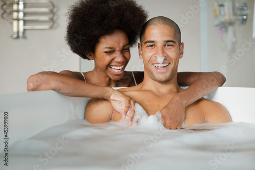 Woman playing with boyfriend in bubble bath