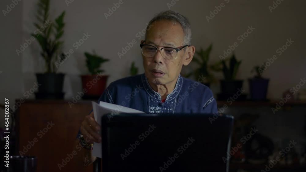 Serious elderly businessman in eyeglasses checking corporate paperwork correspondence sitting at home. Senior male entrepreneur reading documents, analyzing financial papers on working desk at night. Serious elderly businessman in eyeglasses checking corporate paperwork correspondence sitting at home. Senior male entrepreneur reading documents, analyzing financial papers on working desk at night.