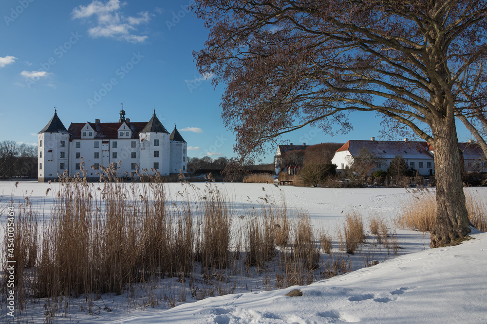 Fairytale water castle with frozen castle pond in dreamlike winter wonderland landsacpe.
