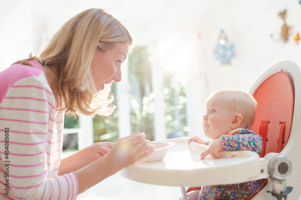 Mother feeding baby girl in high chair Mother feeding baby girl in high chair
