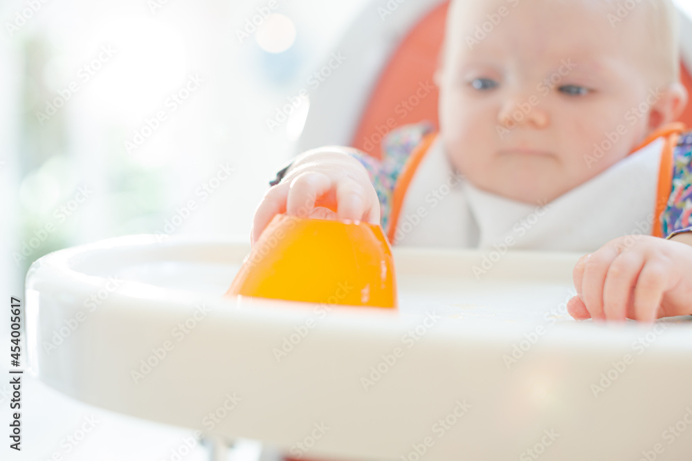Baby girl playing with gelatin dessert in high chair Baby girl playing with gelatin dessert in high chair