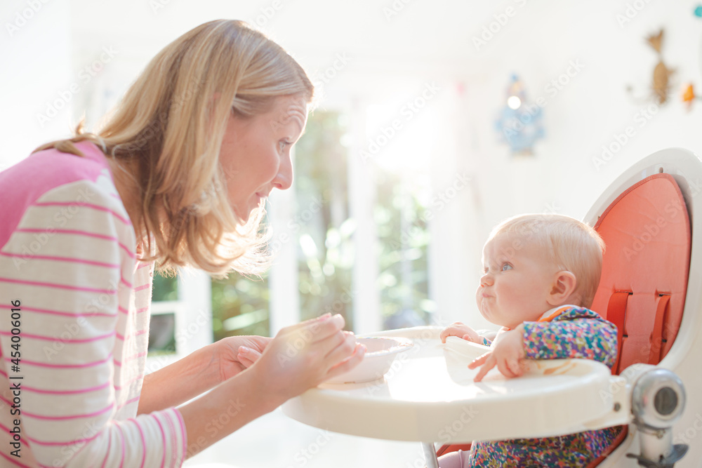 Mother feeding baby girl in high chair Mother feeding baby girl in high chair