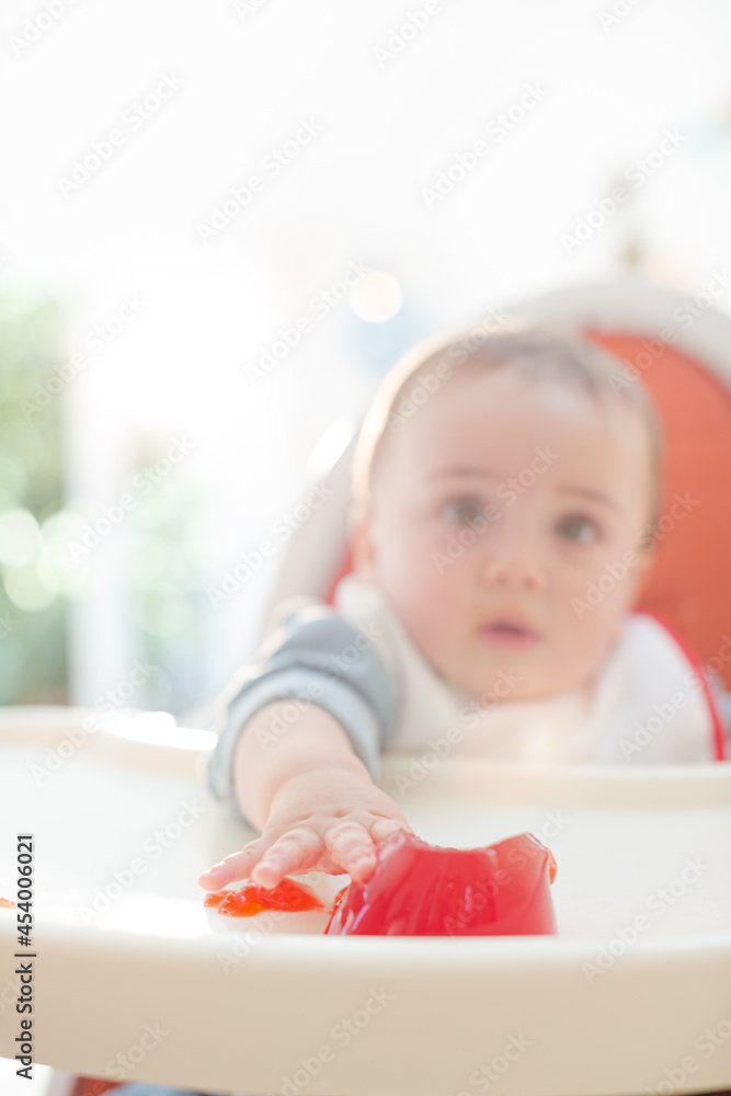 Fototapeta premium Baby boy eating gelatin dessert in high chair