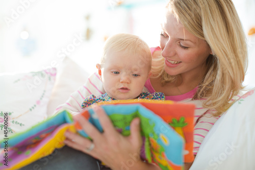 Mother reading to baby girl on sofa
