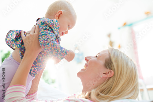 Mother playing with baby girl on sofa