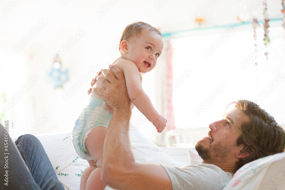 Father playing with baby son on sofa Father playing with baby son on sofa