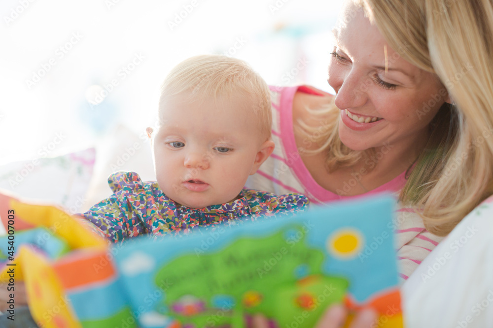 Mother reading to baby girl on sofa Mother reading to baby girl on sofa