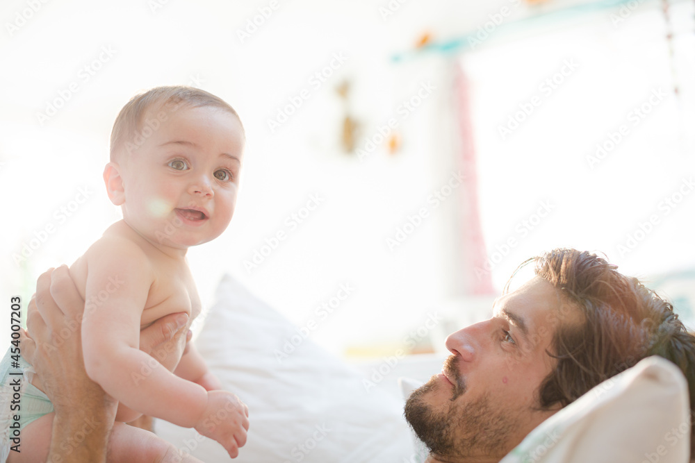 Father playing with baby son on sofa Father playing with baby son on sofa