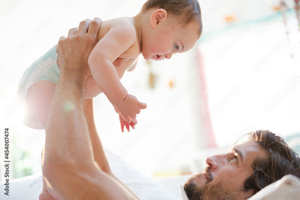 Father playing with baby son on sofa Father playing with baby son on sofa