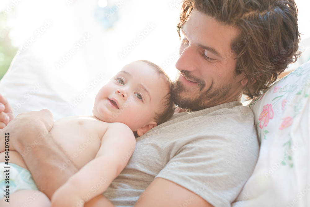 Father laying with baby boy on bed