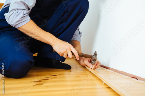 To make repairs. Installing a new skirting board. a man makes repairs in a room