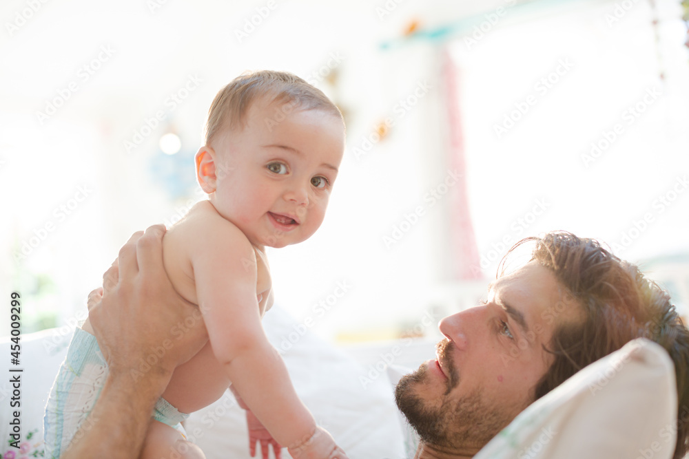 Father playing with baby son on sofa Father playing with baby son on sofa