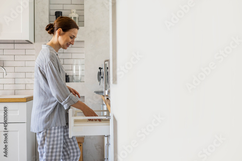 modern housewife tidying up kitchen cupboard during general cleaning or tidying up