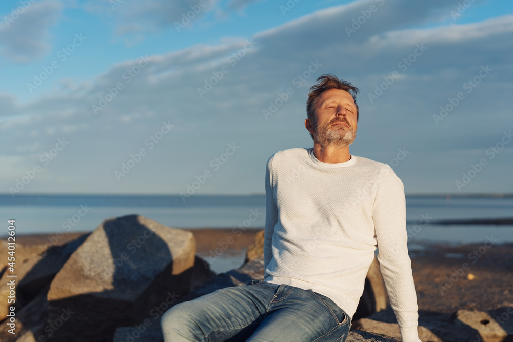 Blissful man taking a moment to relax and meditate at sunset Blissful man taking a moment to relax and meditate at sunset