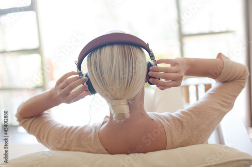Obraz na plátne Woman listening to headphones on sofa