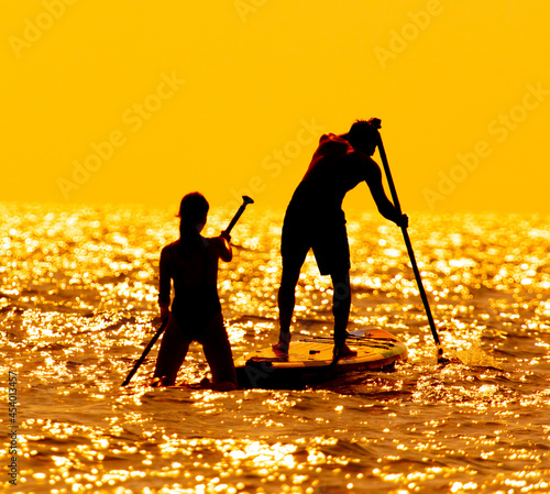 A guy and a girl are sailing on a board in the sea.