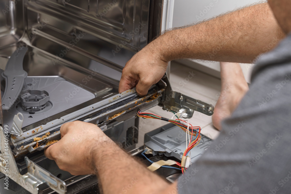 echnician or plumber repairing the dishwasher in a household. the rubber seal is damaged echnician or plumber repairing the dishwasher in a household. the rubber seal is damaged