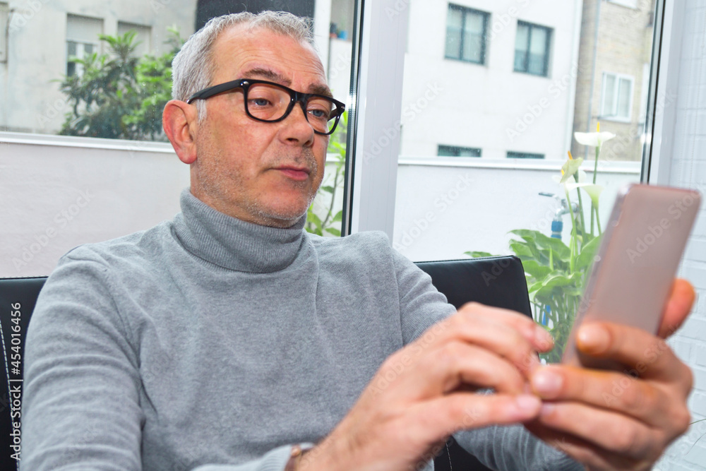 mature man using the phone on the sofa at home mature man using the phone on the sofa at home