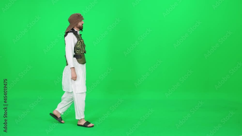 A man of Arab appearance in traditional clothes walking down the street against the green background, man in military equipment, chromakey template. A man of Arab appearance in traditional clothes walking down the street against the green background, man in military equipment, chromakey template.