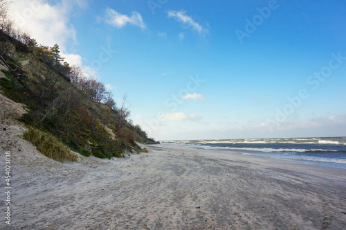 Shot of a beach beneath a grassy hill on a bright day photo