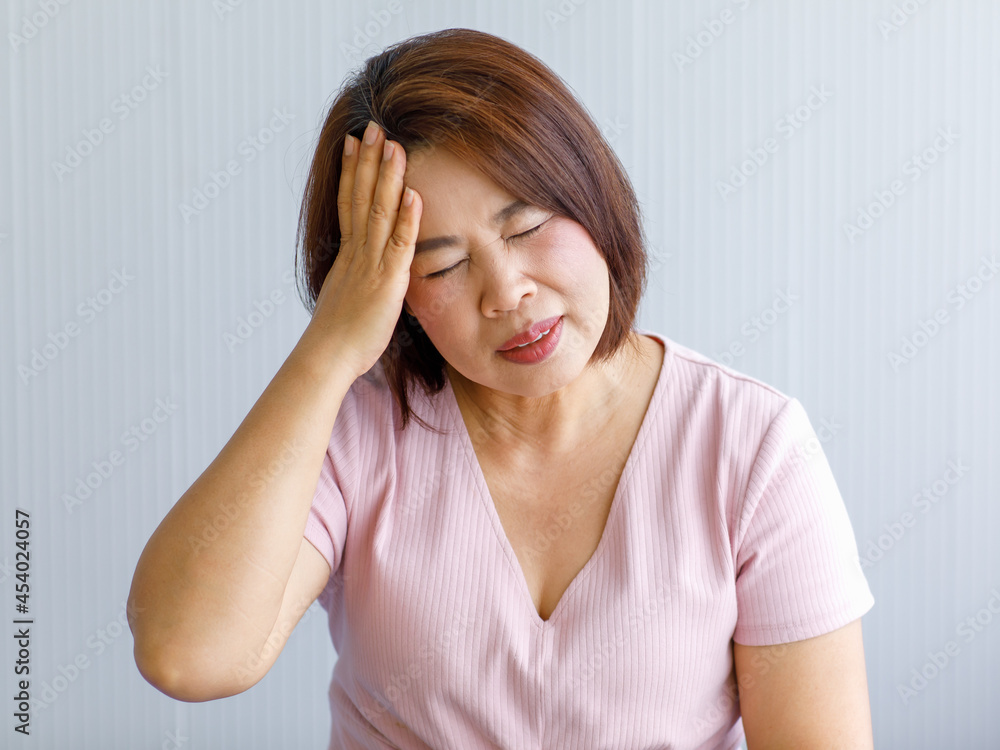 Middle age senior Asian woman feeling pain from sudden headache and brain stroke attack and hold her head with a stressed face. Concept of brain and head problem Middle age senior Asian woman feeling pain from sudden headache and brain stroke attack and hold her head with a stressed face. Concept of brain and head problem