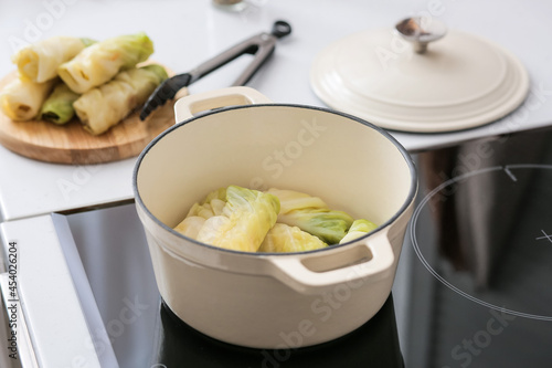 Cooking pot with raw stuffed cabbage rolls on electric stove at kitchen