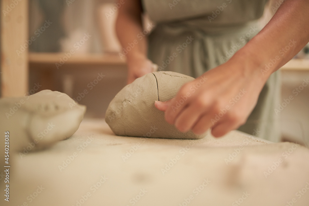 Unrecognizable female artisan dividing clay