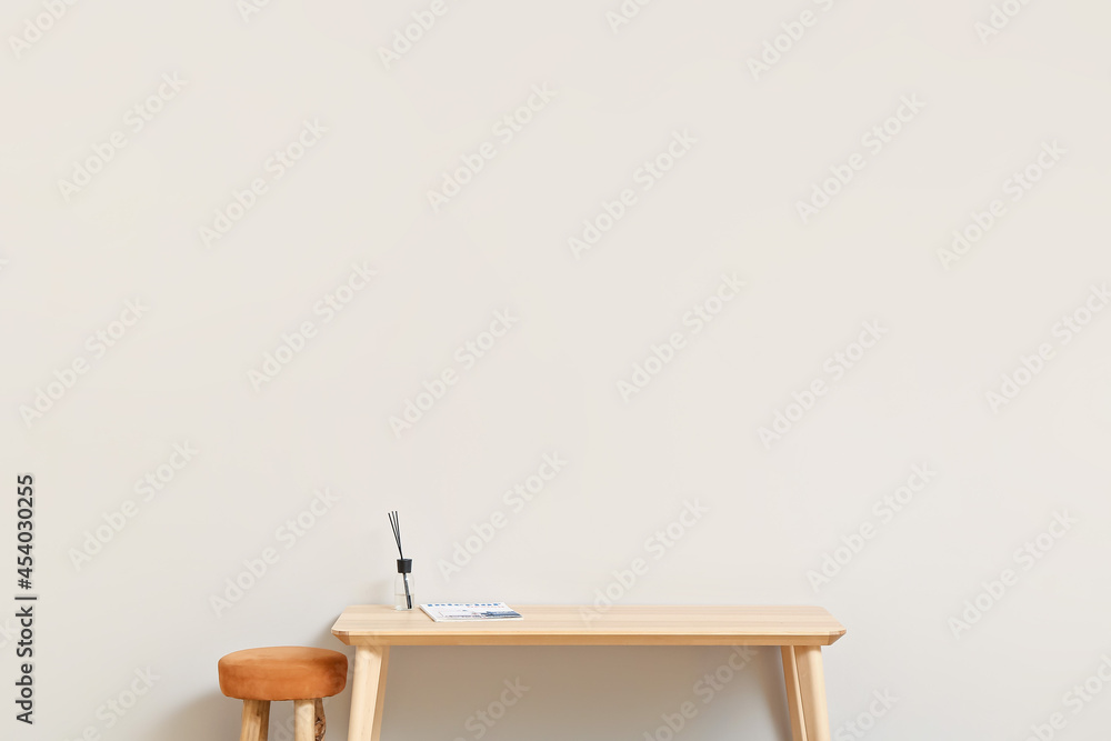 Fototapeta premium TV stand with reed diffuser and chair near light wall