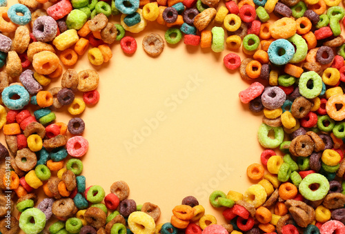 Frame made of tasty cereal rings on color background, closeup