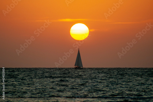 Ocaso en el mar con barco velero photo