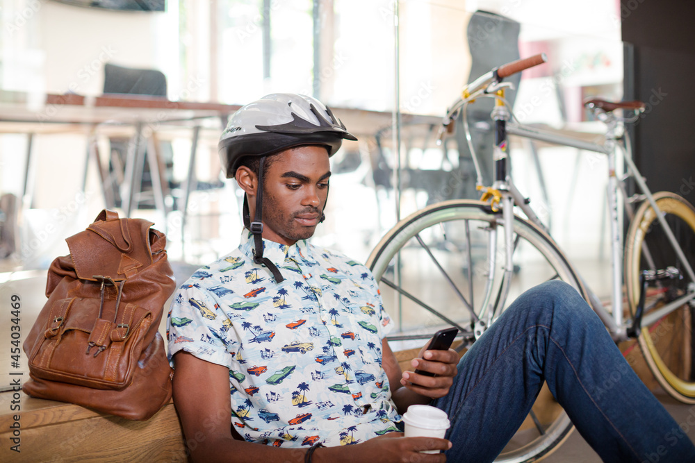 Man in bicycle helmet using cell phone in office Man in bicycle helmet using cell phone in office