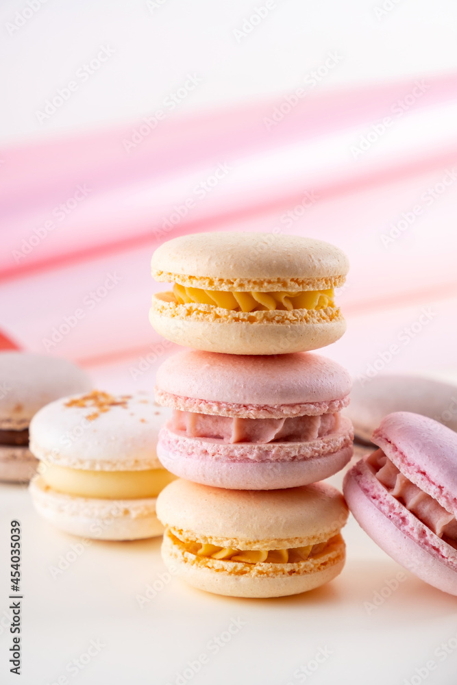Colorful pastel french macaroons or macarons  on white and pink background