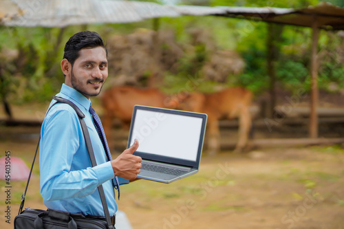 Young indian agronomist or banker showing laptop screen photo