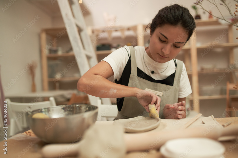 Artisan shaping clay plate with sponge Artisan shaping clay plate with sponge