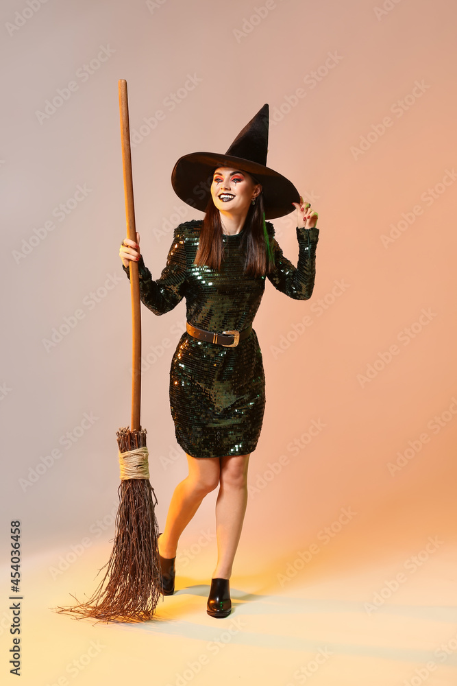 Beautiful woman dressed as witch for Halloween on color background Beautiful woman dressed as witch for Halloween on color background