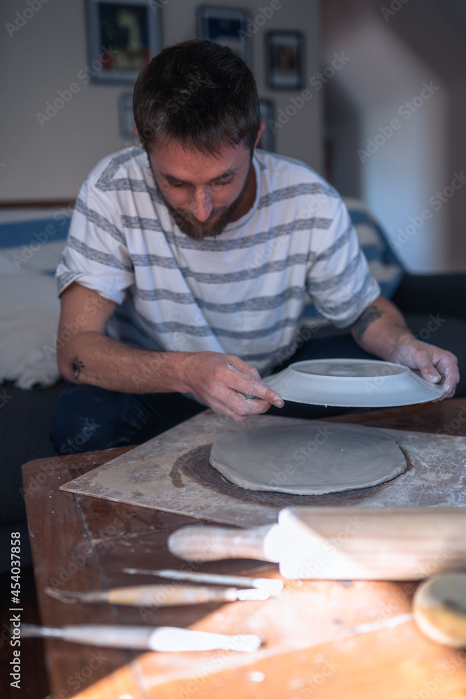 The process of making ceramic crockery. Man making sure plate is round The process of making ceramic crockery. Man making sure plate is round