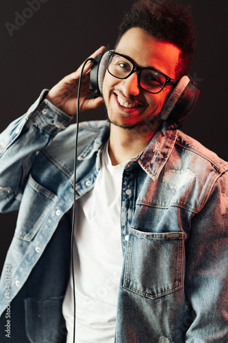 Young African American man wearing headphone and enjoy music over black Background