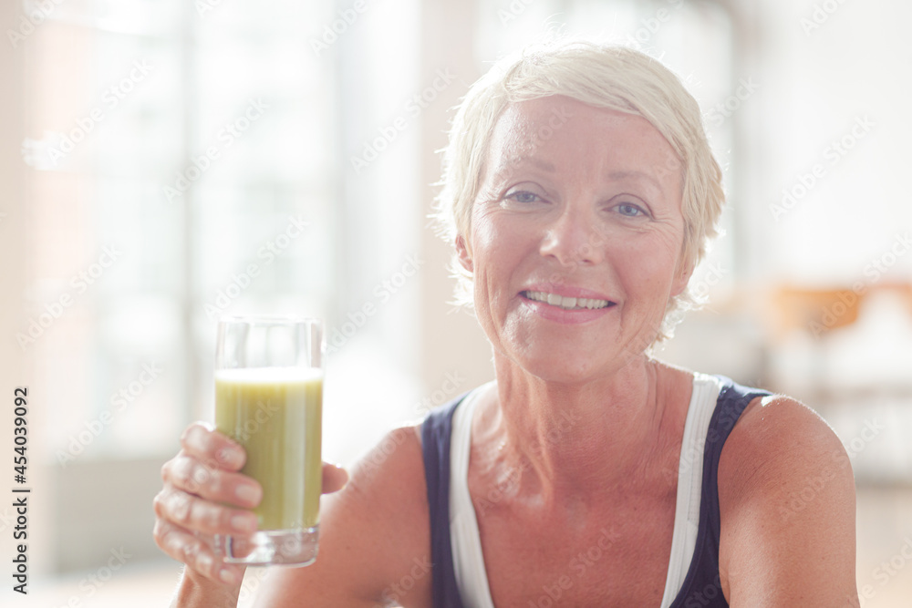 Older woman drinking juice on exercise mat Older woman drinking juice on exercise mat