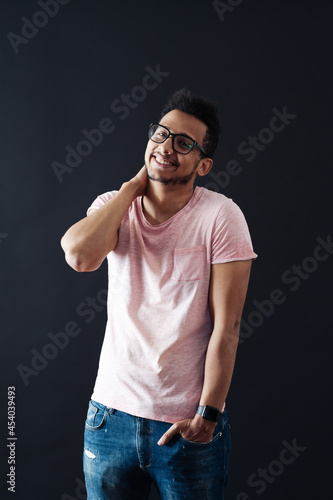 Young handsome man with beard wearing casual t shirt and glasses over black background face smiling looking at the camera. Positive person.
