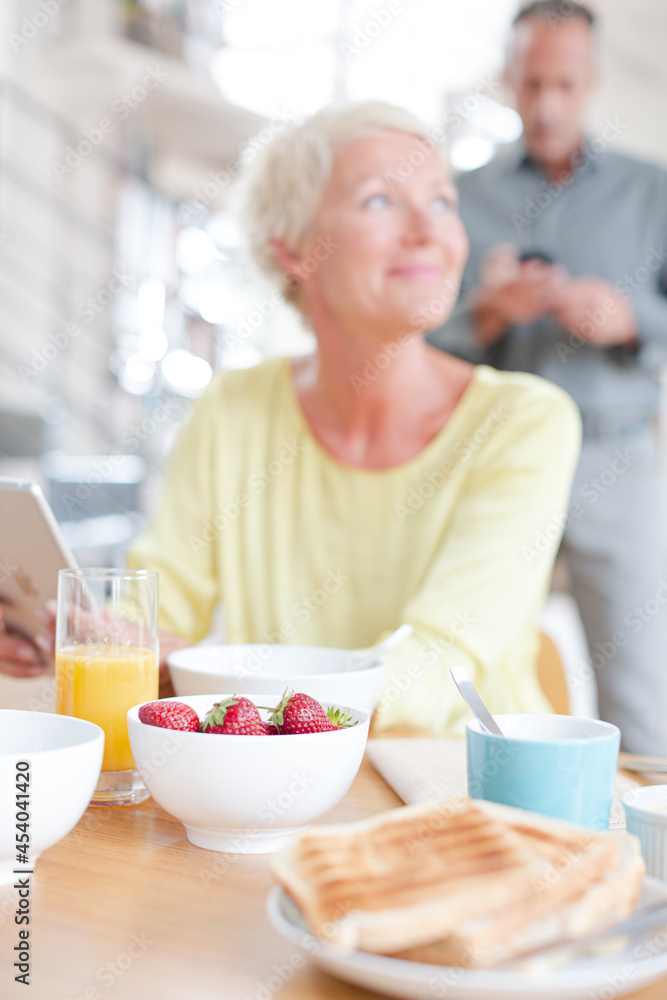 Older woman using digital tablet at breakfast table