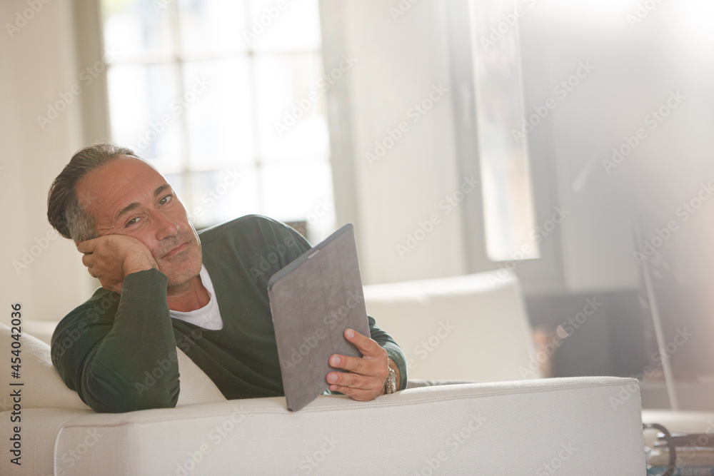 Older man using digital tablet on living room sofa Older man using digital tablet on living room sofa