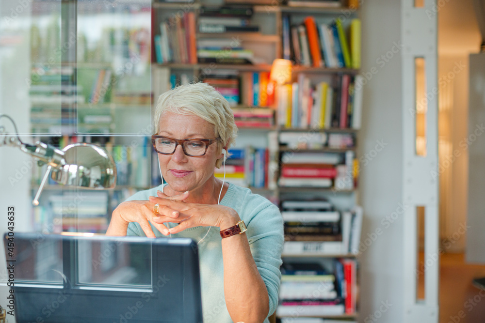 Businesswoman smiling at computer in home office Businesswoman smiling at computer in home office