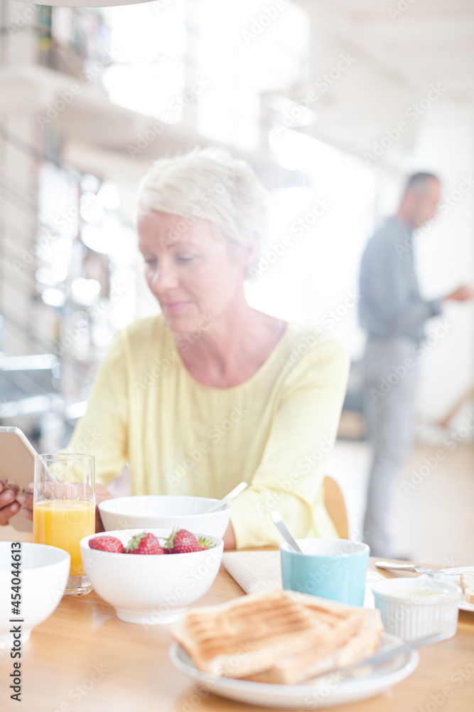 Older woman using digital tablet at breakfast table Older woman using digital tablet at breakfast table