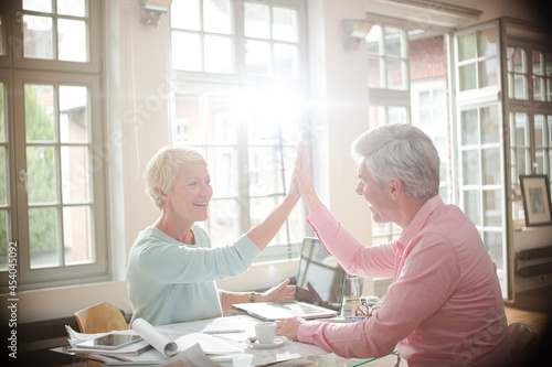 Business people high fiving at home office desk