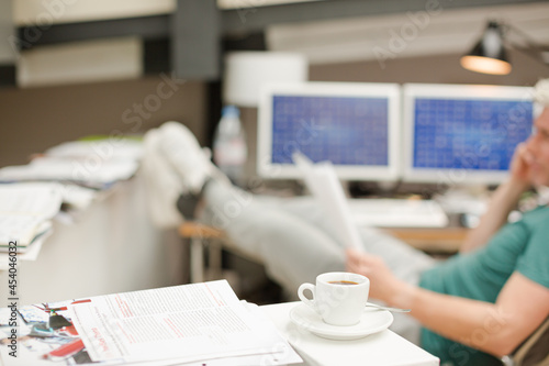 Businessman reading paperwork in office behind coffee cup