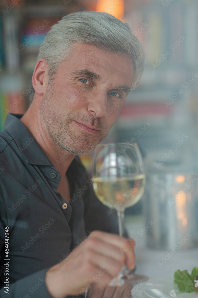 Smiling older man toasting with white wine