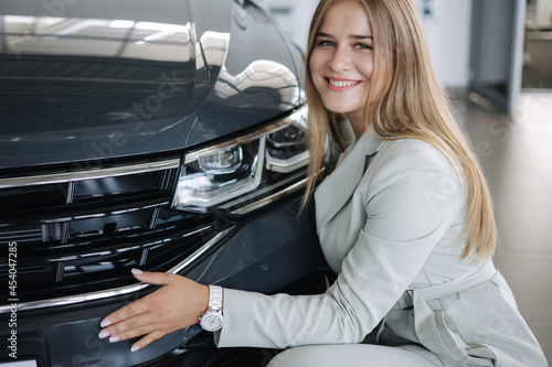 Business woman chossing a new car in a car showroom. Happy female hug new car and very glad © Aleksandr